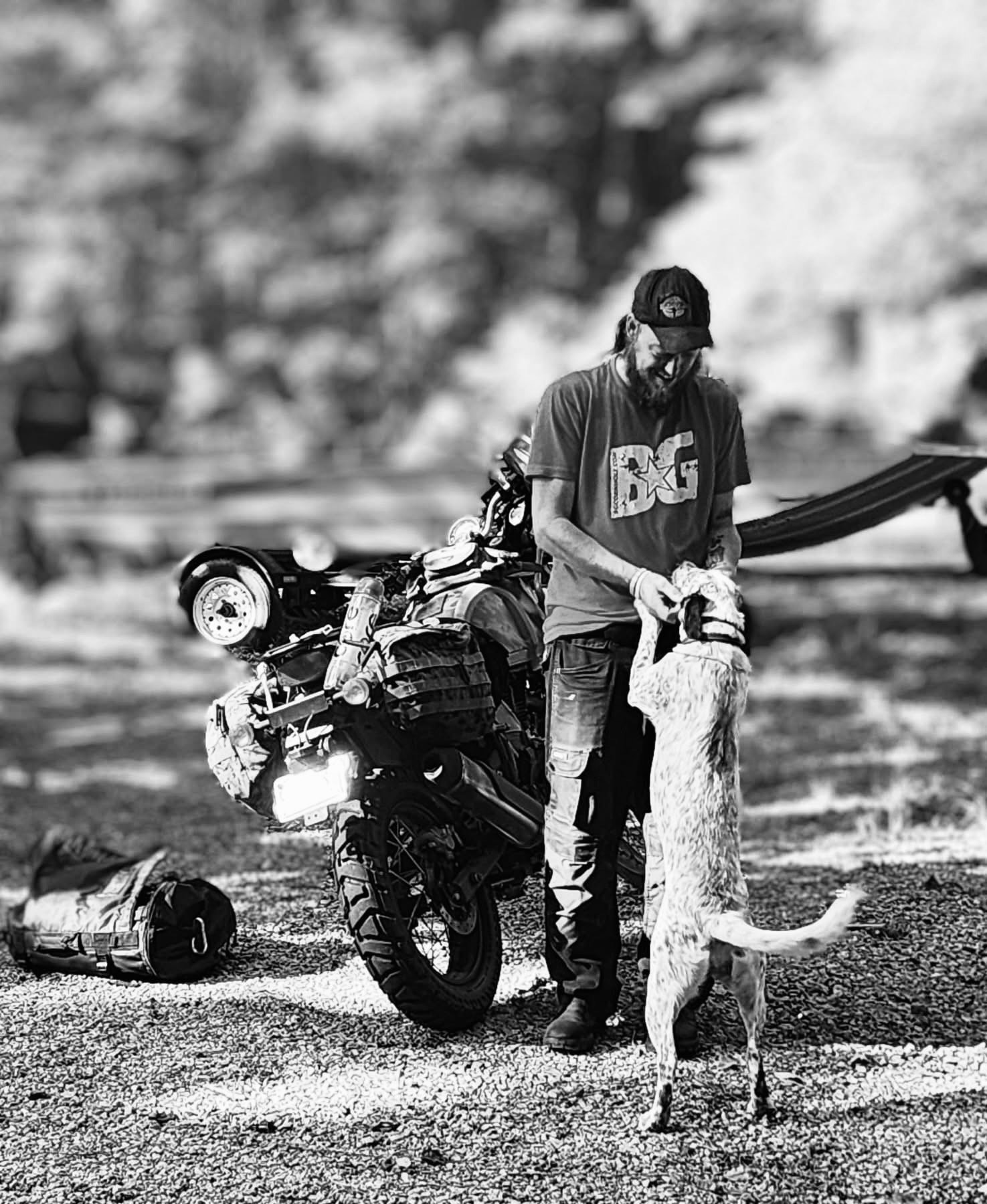 Rider with loaded adventure motorcycle and dog at camp